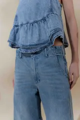 Pantalón de jean color beige, de tiro medio, corte amplio y ruedo acampanado.