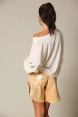 Blusa color crema de gasa con escote asimétrico y manga larga.