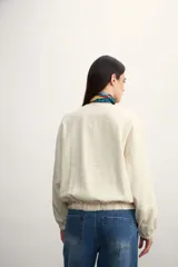 Chaqueta bomber negra con cierre frontal dorado y mangas largas con puños elásticos.