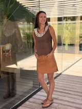 Top negro de cuero con escote en V y apliques de caracoles cosidos a mano en el escote.