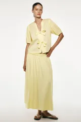 Camisa color amarillo claro de popelín con lyocell, cuello redondo con escote pico, manga corta con elástico y cierre frontal con lazadas.