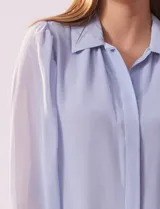 Camisa celeste de gasa, marca Tahari. Cuello con solapa y abertura central con botones ocultos. Manga larga abullonada con puño y botones. Forro de gasa a tono.