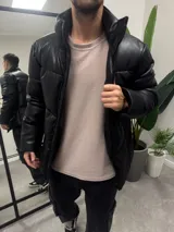 Campera puffer negra de símil cuero, con cuello alto y cierre frontal con cremallera.