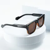Lentes de sol Berna con montura gruesa color negro y caramelo, de forma cuadrada y cristales marrones.