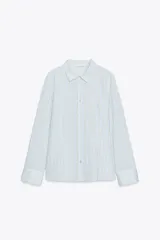 Camisa celeste con rayas verticales en blanco y amarillo, de corte entallado, cuello solapa y manga larga.