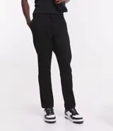 Pantalón de vestir marrón, de corte skinny, con bolsillos laterales y traseros. Se ajusta a la cintura con cinturón de cuero marrón.