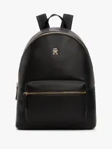 Mochila negra de poliuretano con cierre de cremallera, asa superior, correas ajustables, bolsillo interior con cremallera, bolsillo exterior con cremallera, insignia del monograma TH en la parte delantera y correas de textil trenzado con la inscripción de Tommy Hilfiger.