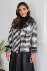 Campera corta con estampado pata de gallo en blanco y negro, cuello y puños de cuero sintético negro, doble botonadura y corte holgado.