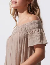 Blusa color beige de gasa bambula, marca Liv Los Ángeles. Escote recto con frunce y hombros descubiertos. Manga corta con detalles bordados.