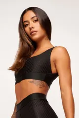 Top deportivo negro con textura colmena 3D, escote cuadrado, breteles anchos y banda inferior con logo.