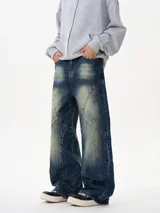 Jean de mezclilla azul oscuro con lavado desgastado y paneles con costuras diagonales pronunciadas, de corte ancho y holgado.