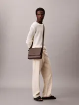 Cartera tipo mensajero con solapa y cierre magnético, confeccionada en piel sintética texturizada (micro pebble). Presenta correa ajustable y múltiples bolsillos interiores.