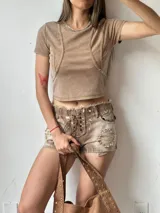 Short de jean color marrón claro con efecto desgastado, tiro alto, cierre con cordones cruzados y detalles rotos.