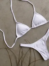 Conjunto de bikini verde esmeralda, con corpiño triangular de atar al cuello y espalda, con almohadillas desmontables, y bombacha colaless con laterales fijos.