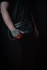 Bandolera negra de cuero sintético con correa ancha ajustable y desmontable. Cuenta con cierre superior, bolsillo frontal con tiracierre customizado, forro interno y cuatro bolsillos en total (dos exteriores y dos interiores).