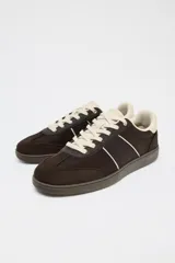 Zapatillas deportivas marrones con detalles en color crema y suela plana.