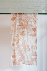 Pañuelo rectangular de seda color crema con estampado botánico en tonos naranja y marrón, realizado con hojas de eucalipto y casuarina.