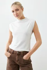 Remera blanca de corte ajustado, con cuello alto y sin mangas.