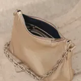 Cartera tipo baguette de cuero color rojo brillante, con correa de cadena plateada.