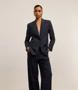 Pantalón de vestir azul marino, de corte wide leg, con cintura alta, bolsillos laterales y traseros. Se ajusta a la cintura con cinturón de cuero marrón.