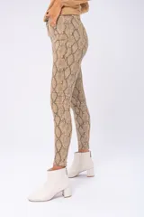 Pantalón de jean ajustado con estampado de piel de serpiente en tonos marrones.