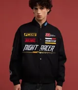 Campera negra con cuello alto, cierre de botones y estampado estilo racing con logos y textos en amarillo, rojo y blanco. Tiene bolsillos laterales y mangas largas con detalles estampados. Marca Blue Steel.
