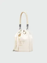Bolso tipo bucket de cuero color gris con logo "The Bucket Marc Jacobs" estampado en negro. Tiene asa corta de cuerda trenzada y correa larga de cuero ajustable y removible.