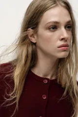 Chaqueta de punto liso color rojo, confeccionada en 100% lana. Tiene cuello redondo, manga larga, terminaciones en rib y cierre frontal con botones.