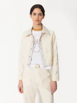 Chaqueta corta color crema de canvas con detalles en cuero genuino en cuello y cartera. Diseño con bordados de hongos y chiles intervenidos con strass.