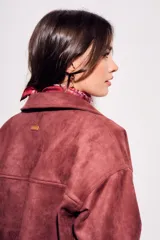 Sobrecamisa color borgoña de gamuza sintética con cuello camisero, cierre frontal con botones a tono, bolsillos de parche con solapa en el pecho y mangas largas con puños abotonados.