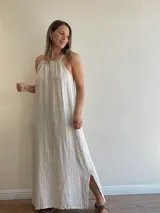 Vestido largo de lino color crudo, con escote halter fruncido y abertura lateral en la falda.