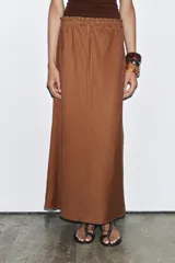Falda midi color marrón confeccionada en lino 100%. Tiene tiro medio, cintura elástica ajustable con cordones y bajo evasé.