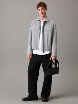 Bolso bandolera negro de Calvin Klein, confeccionado en piel sintética suave. Tiene correa ancha ajustable, cierre de cremallera, bolsillo exterior y bolsillo interior.