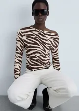 Camiseta de manga larga con estampado animal print de cebra en tonos marrones y beige. Tiene cuello asimétrico y corte ajustado.