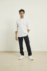 Camisa blanca de algodón premium, corte clásico, cuello inglés, cartera abotonada, mangas largas con puños ajustables y bajo redondeado.