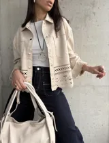 Sobrecamisa color beige de gamuza sintética con cuello camisero, cierre frontal con botones dorados, bolsillos de parche en el pecho y bajo con calados.