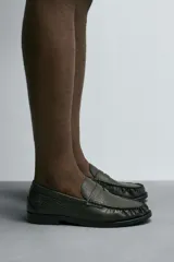 Mocasín de vestir color marrón oscuro con grabado tipo cocodrilo, horma redonda y suela con ligero tacón.