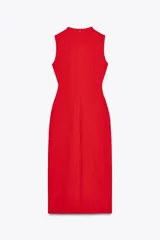 Vestido midi color crema, de cuello redondo y sin mangas. Presenta falsos botones frontales, cinturón elástico con aplique dorado, bolsillos de parche con solapa y abertura delantera.