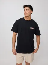Remera negra de algodón con cuello redondo y manga corta. Estampado frontal con el logo de Rusty en color naranja, blanco y rojo.