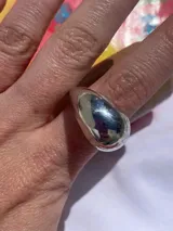 Anillo plateado de metal con forma redondeada y diseño chunky.