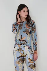 Sweater celeste de cashmere con estampado de tigres y hojas en tonos marrones y beige.