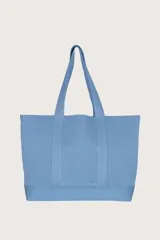 Bolso tipo tote grande color celeste, con textura acanalada vertical y asas de hombro.