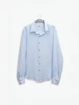 Camisa celeste de lino, de manga larga con botones de coco y parche de la marca.