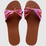 Sandalias Havaianas You St Tropez con base marrón y tira de tela estampada con rayas de colores y nudo decorativo.