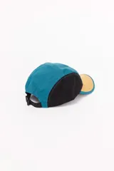Gorro de visera de cinco paneles con diseño color block en azul, amarillo y negro. Presenta un parche con logo en el panel frontal.