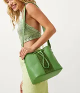 Bolso tipo bucket verde con correa transversal tejida, detalle trenzado en la parte delantera, colgante de borla y cierre con botón a presión.