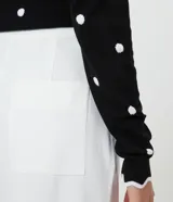 Pantalón wide leg blanco confeccionado en crepé, con botones dorados en los laterales, bolsillos y cierre con botón y cremallera.