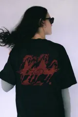 Remera negra de manga corta con estampado serigrafiado en la espalda de caballos galopando en tonos rojizos, con llamas y un logo central ovalado.