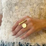 Anillo dorado con forma geométrica de círculo y línea, hecho artesanalmente en bronce y de tamaño regulable.