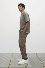 Pantalón cargo color marrón topo, de corte relajado, confeccionado en popelina de algodón. Cuenta con bolsillos al bies, bolsillos traseros con solapa y bolsillos laterales en las piernas con solapa y botones a presión.